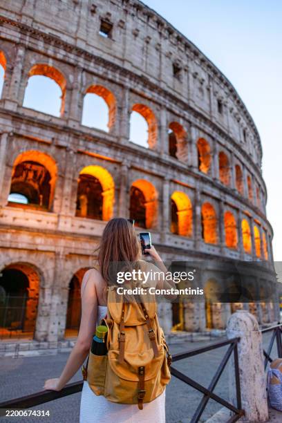 vista trasera de una mujer tomando fotos del coliseo al atardecer - provincia de roma fotografías e imágenes de stock