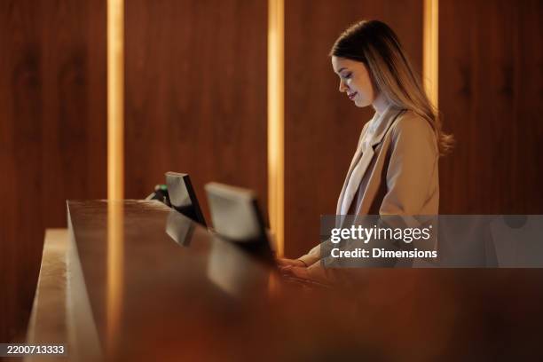 hotel receptionist working at computer in lobby - lobby stock pictures, royalty-free photos & images