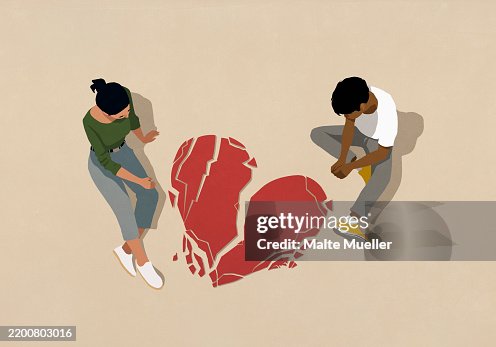 High angle view couple looking down at broken heart on beige background High angle view couple looking down at broken heart on beige background