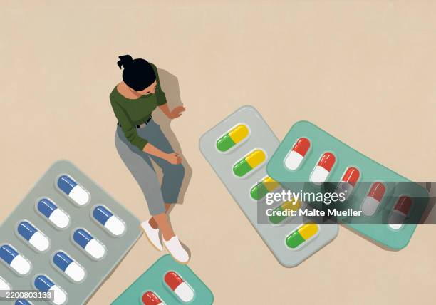high angle view woman looking down at large medication in blister packs - opioid stock illustrations
