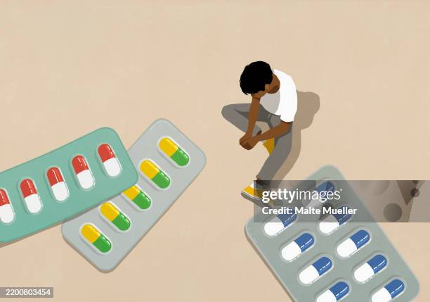 high angle view man looking down at large medication pills in blister packs - drug abuse stock illustrations