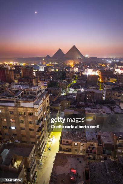 the stark contrast between the city of cairo and the iconic pyramids make for a stunning view during the blue hour, cairo, egypt, africa - cairo stock pictures, royalty-free photos & images
