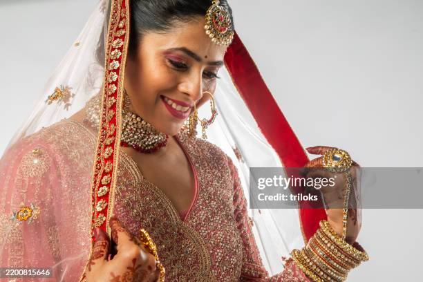smiling bride in pink wedding dress standing on white background - beautiful indian women for marriage stock pictures, royalty-free photos & images