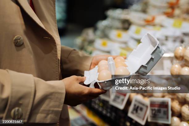 primer plano de una empresaria asiática comprando comestibles en un supermercado. sostiene una caja de huevos orgánicos frescos de gallinas camperas. estilo de vida de alimentación saludable. - óvulo fotografías e imágenes de stock