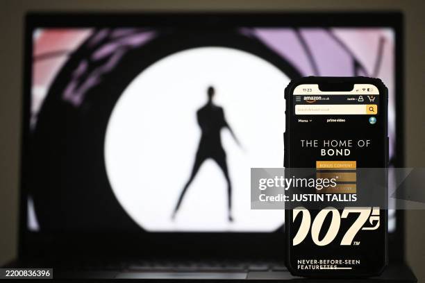 In this photo illustration created in London on February 23, 2025 the Amazon.co.uk app displays "The Home Of Bond" on a phone screen next to an...