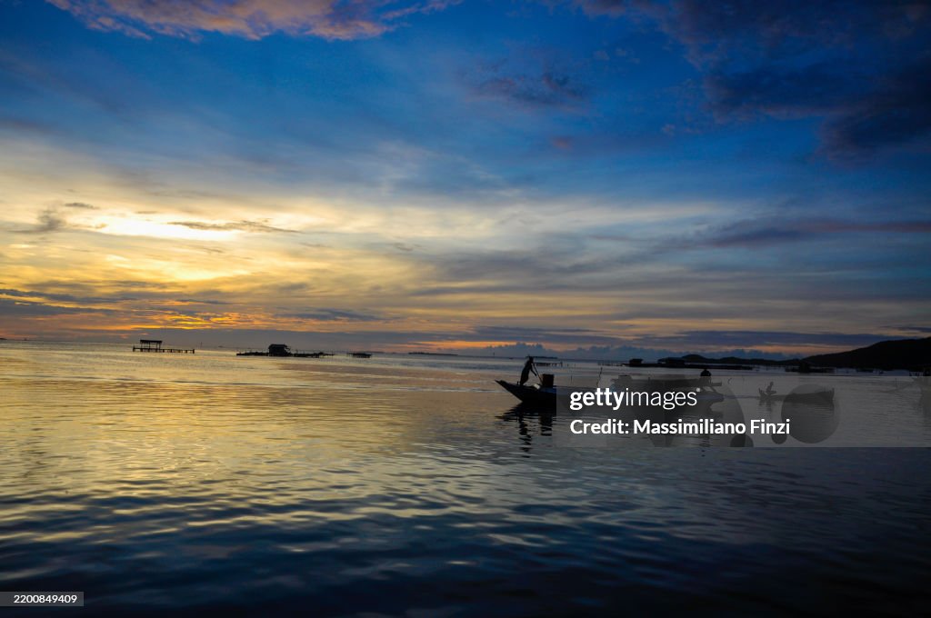 Water surface. View of a Sunset sky background. Dramatic gold sunset sky with evening sky clouds over the sea with a boat in silhouette.