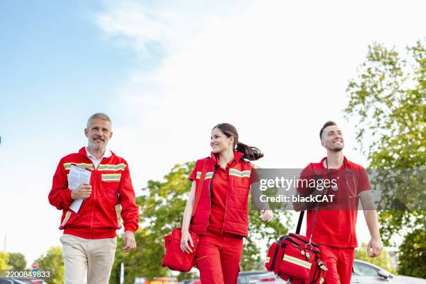 group of emergency medical professionals walking outdoors in team uniforms - openbare dienstverlening stockfoto's en -beelden