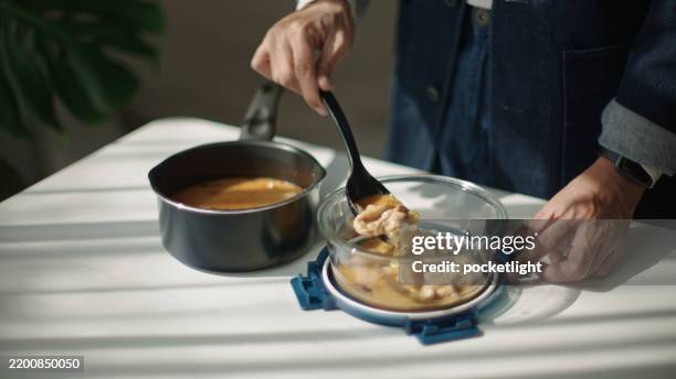 verser les restes de soupe dans un récipient en verre durable. - réfrigérateur fermé photos et images de collection