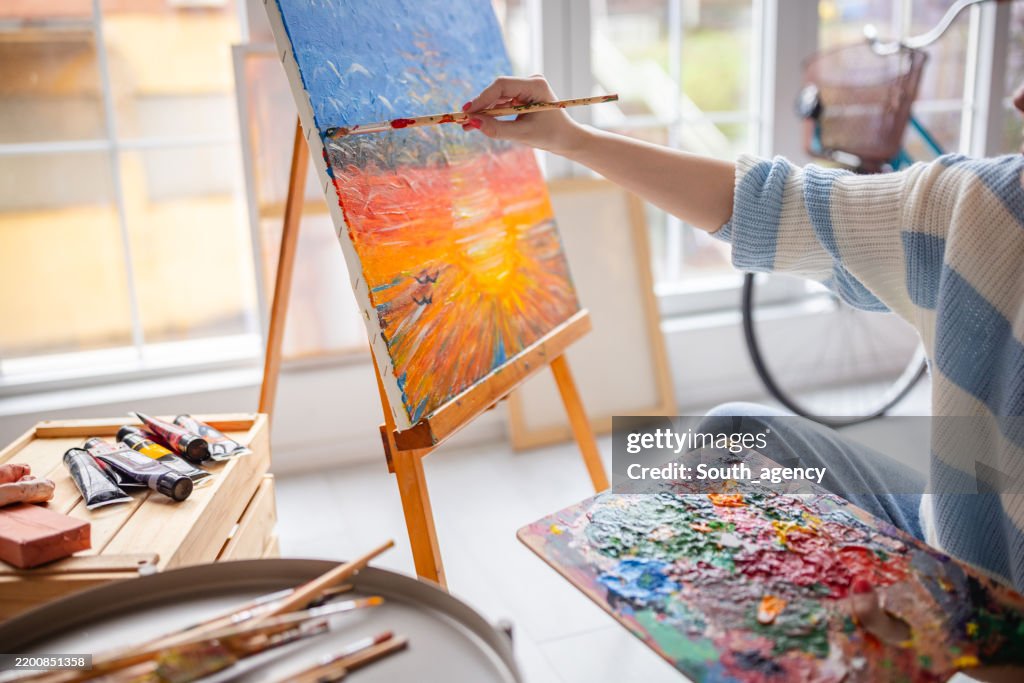 Young artist enjoys painting in her cozy home studio while expressing her creativity on a beautiful weekend afternoon