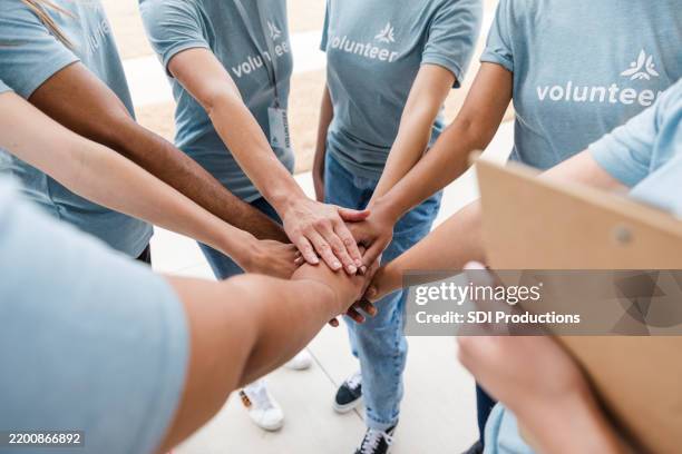 diverse group of volunteers stacking hands, teamwork concept - huddling stock pictures, royalty-free photos & images