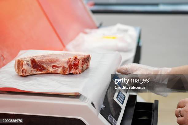 professional scale displays exact weight of raw meat piece. butcher in protective gear handles premium cut at retail counter - exact_(company) stock pictures, royalty-free photos & images