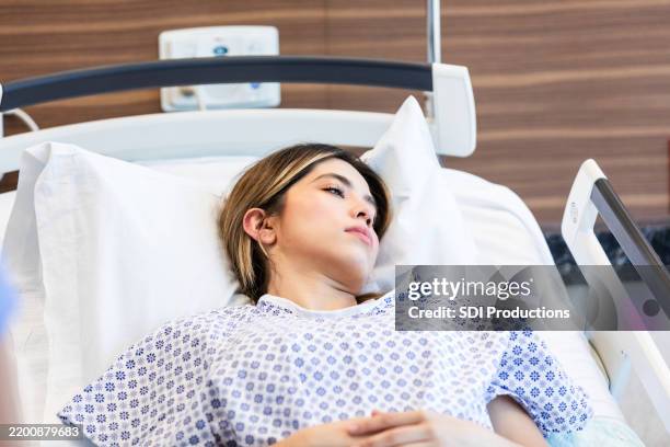young woman resting in hospital bed, healthcare, patient - female patient in examination gown lying down on stretcher stock pictures, royalty-free photos & images