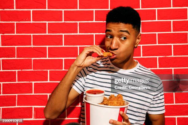 young man enjoying crispy chicken - eating chicken wing stock pictures, royalty-free photos & images