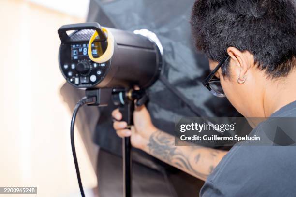 photographer adjusting lighting equipment during studio photoshoot - behind the scenes stock pictures, royalty-free photos & images
