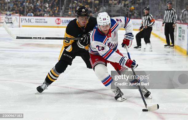 Adam Fox of the New York Rangers skates with the puck against Cody Glass of the Pittsburgh Penguins in the first period during the game at PPG PAINTS...