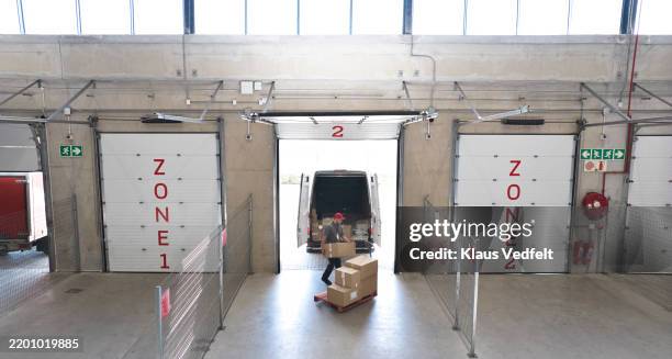 worker loading cardboard boxes in delivery van - muelle de carga fotografías e imágenes de stock
