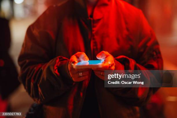 midsection of young woman using smartphone under red neon light - gps stock-fotos und bilder