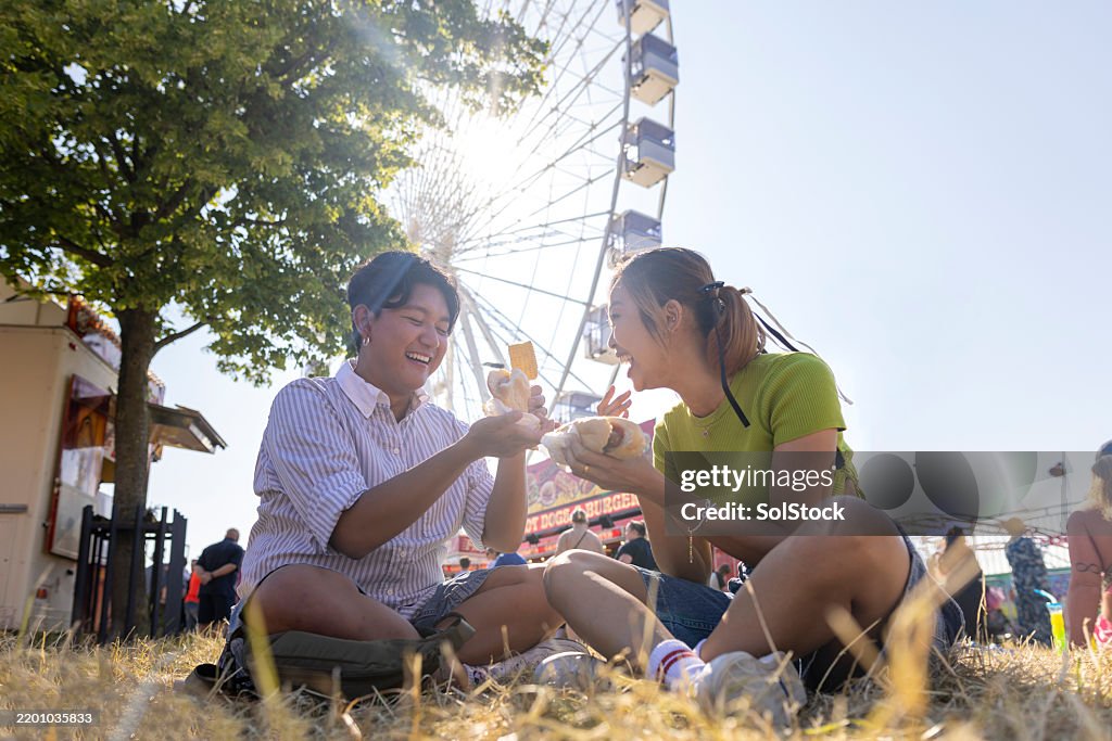 Friends Laughing Together Whilst Enjoying Hotdogs