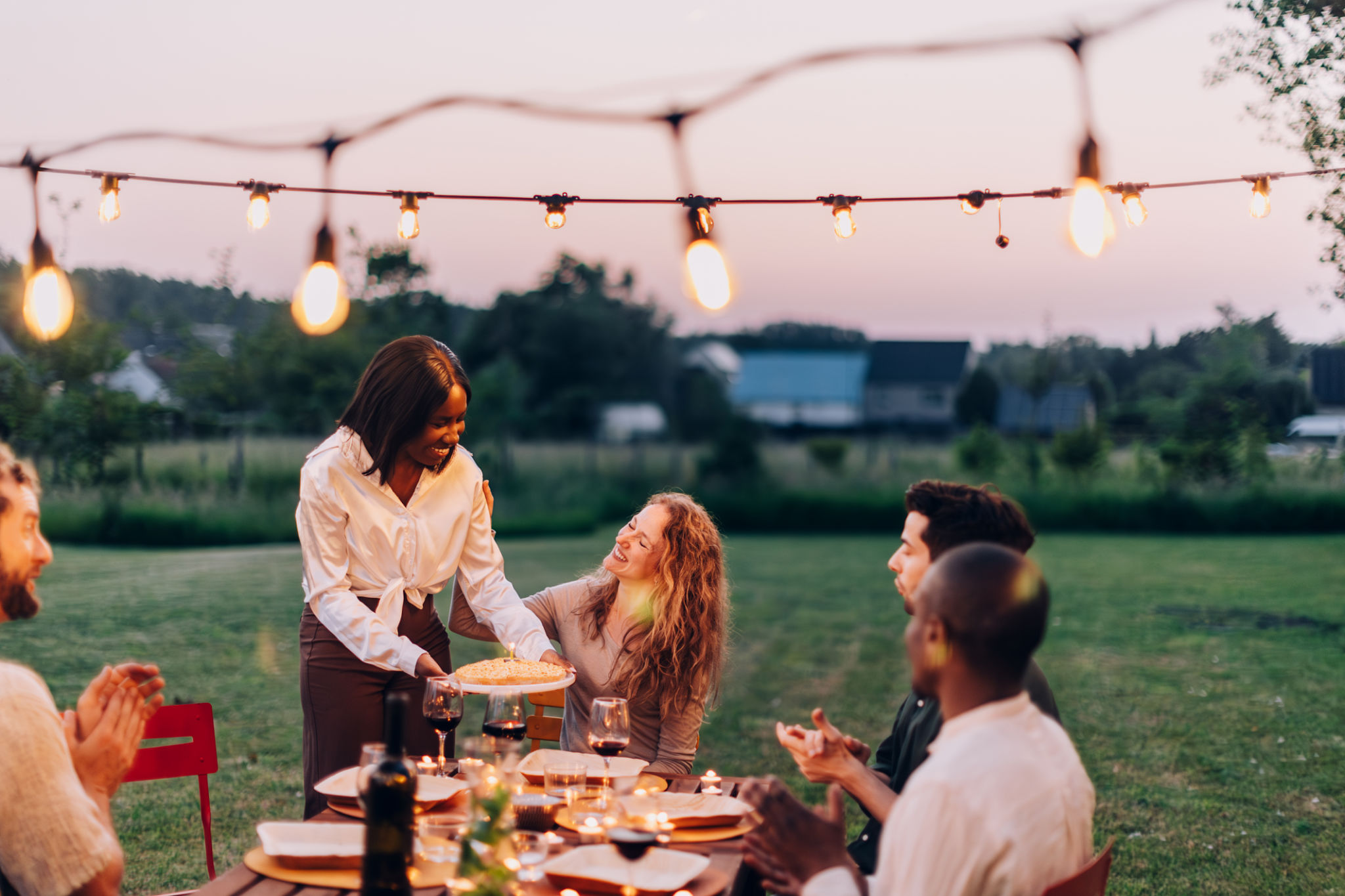 Friends enjoying a dinner party outdoors at sunset Friends enjoying a dinner party outdoors at sunset