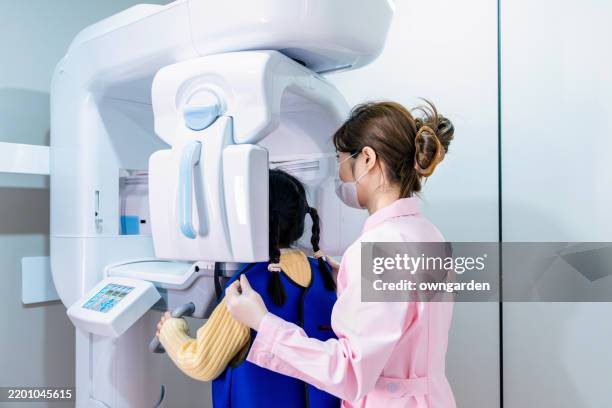 dentist / technician doing teeth x-ray to a little girl - radiologia dental fotografías e imágenes de stock