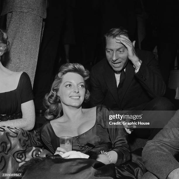 American actress and singer Julie London, wearing a scoop neck outfit, with a drink in her hands, as British-born American pianist, composer,...