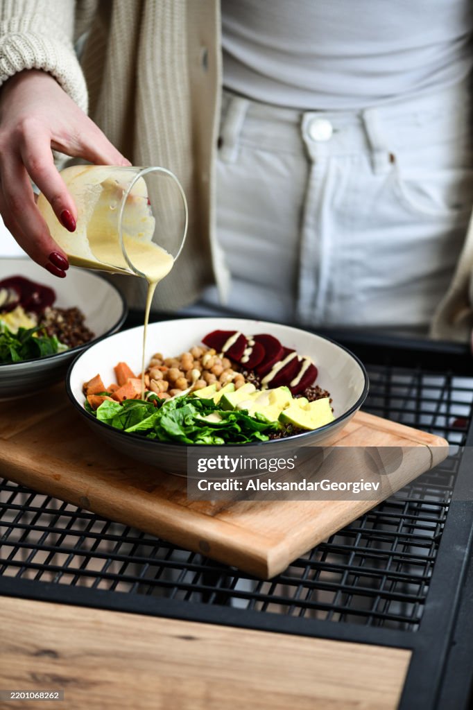 Female Enjoying Healthy Food Cooking Adding Homemade Dressing to Salad Bowl