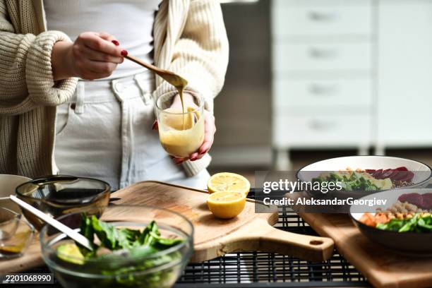 mujer que prepara y revuelve aderezo para ensaladas en vidrio para coloridos cuencos de buda - aliño para la ensalada fotografías e imágenes de stock