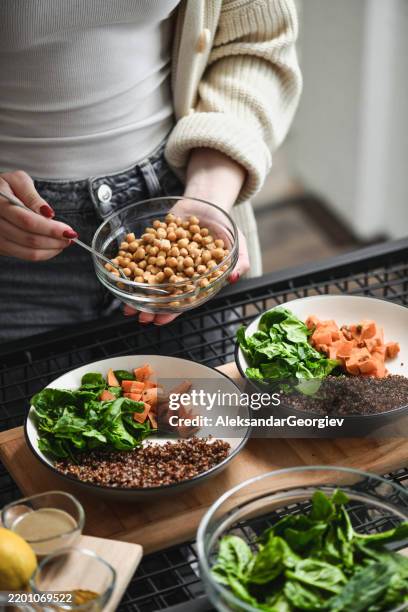 female making colorful buddha bowls showing dieting can be fun and delicious - cooked spinach stock pictures, royalty-free photos & images