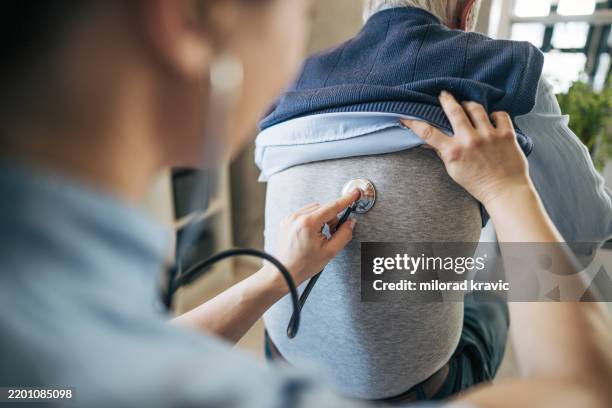 médico examina los pulmones de un anciano con estetoscopio en visita domiciliaria - enfermedad-pulmonar-obstructiva-crónica fotografías e imágenes de stock
