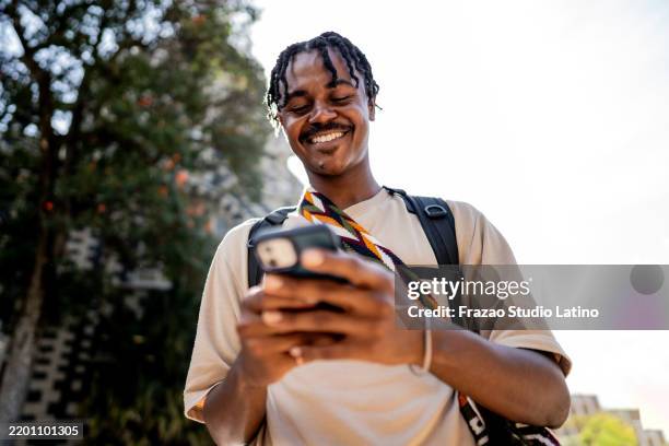 young man using mobile phone outdoors - backpacker city stock pictures, royalty-free photos & images