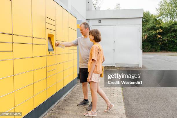 father and daughter collecting parcel from terminal - locker stock pictures, royalty-free photos & images