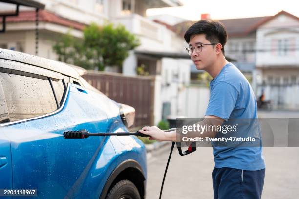 asian man washing his car in front of his home - remove hood stock pictures, royalty-free photos & images