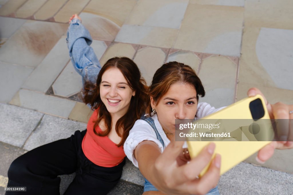 Happy gay couple taking selfie on footpath