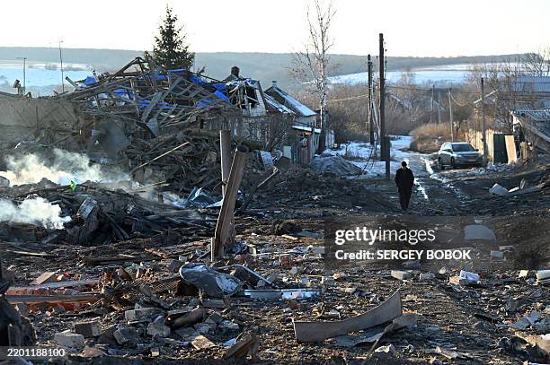 Man walks near a destroyed private house after the explosion of an aerial guided bomb in Kharkiv region on February 24 on the third anniversary of...