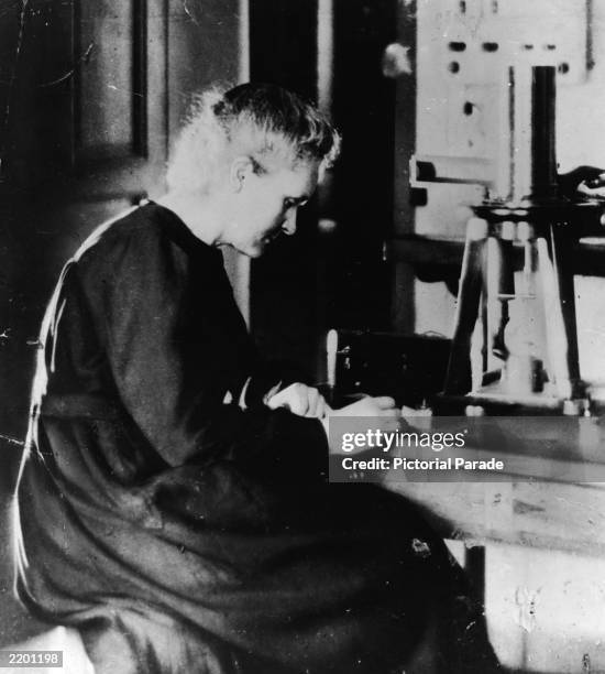 Polish Nobel Prize-winning chemist Marie Curie working at her laboratory desk next to a large burner, c. 1920.