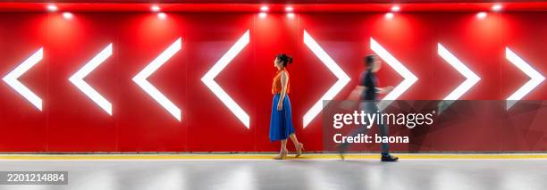 un homme et une femme marchant dans les directions opposées des flèches devant un mur rouge. conflit d’opinions, divorce. - divorce photos et images de collection