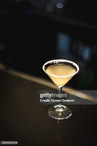 classic margarita cocktail in a sugar-rimmed martini glass, refreshing summer drink with a blurred natural outdoor background, elegant mixology and cocktail culture concept - daiquiri stock pictures, royalty-free photos & images