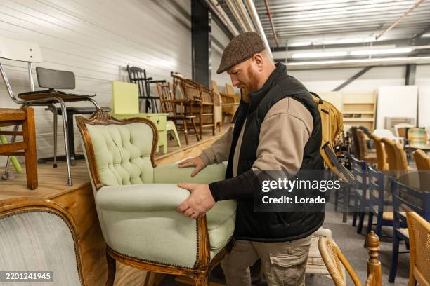redhead senior man looking through the bargains in a public second hand store - kringloopwinkel stockfoto's en -beelden