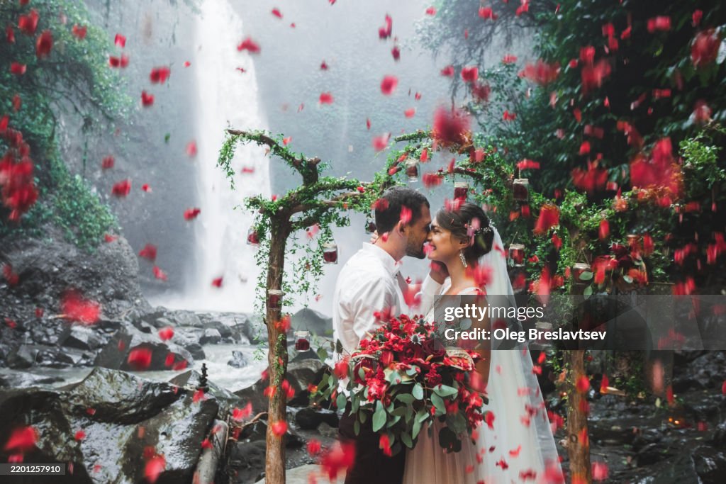 Romantic Outdoor Wedding Ceremony by a Scenic Waterfall with Flower Petals