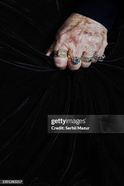 the hand of an elderly person is adorned with various precious rings, clenched into a fist against a black background. - stoffballen stock-fotos und bilder