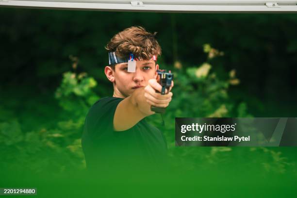 pentathlete with laser pistol during shooting practice, training for international level competition, green trees as background - telelens stockfoto's en -beelden