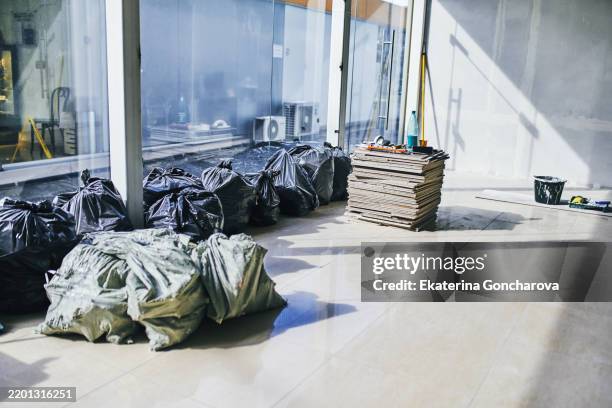 indoor renovation scene with trash bags and construction materials - smaltimento rifiuti foto e immagini stock