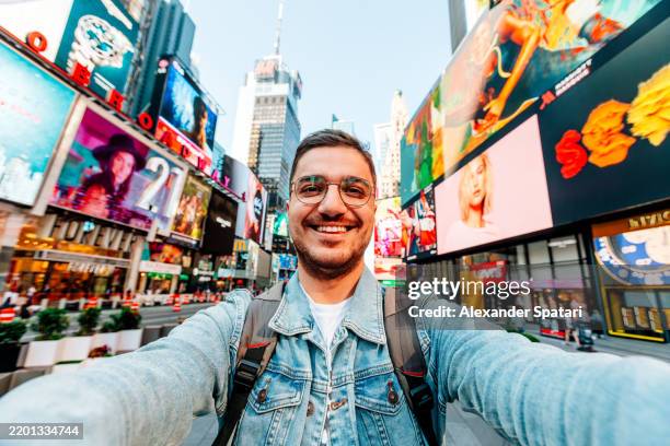 happy smiling man taking selfie on times square on a sunny day, new york city, usa - photo messaging stock pictures, royalty-free photos & images