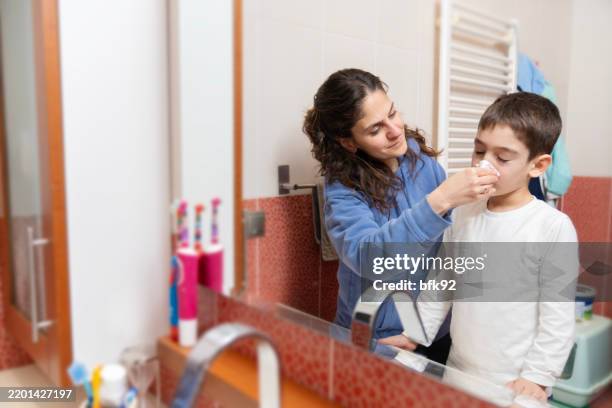 madre limpiando la nariz de su hijo enfermo. - nariz humana fotografías e imágenes de stock