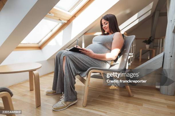pregnant woman writing on the diary at home - cute pregnancy photo ideas stock pictures, royalty-free photos & images