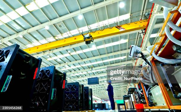 Staff member lifts all vanadium flow energy storage battery accessories at an energy storage battery production line in Zhangye, China, on February...