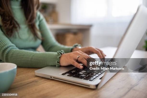 mujer sonriente que trabaja desde casa en la cocina usando una computadora portátil - acercarse fotografías e imágenes de stock