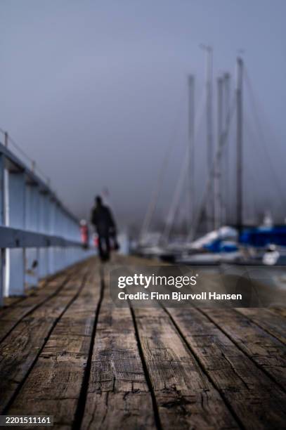 misty marina walkway with a lone figure in soft focus - finn bjurvoll stock pictures, royalty-free photos & images