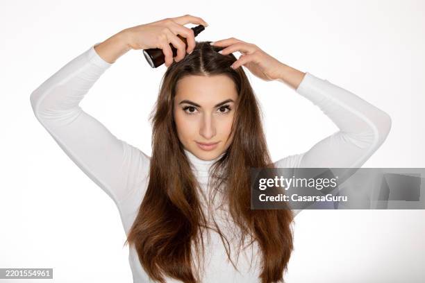 mujer aplicando un producto para el cuidado del cabello en su cuero cabelludo - cuero cabelludo fotografías e imágenes de stock