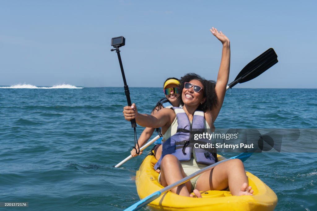 Two cheerful tourists kayaking and taking a selfie with action camera